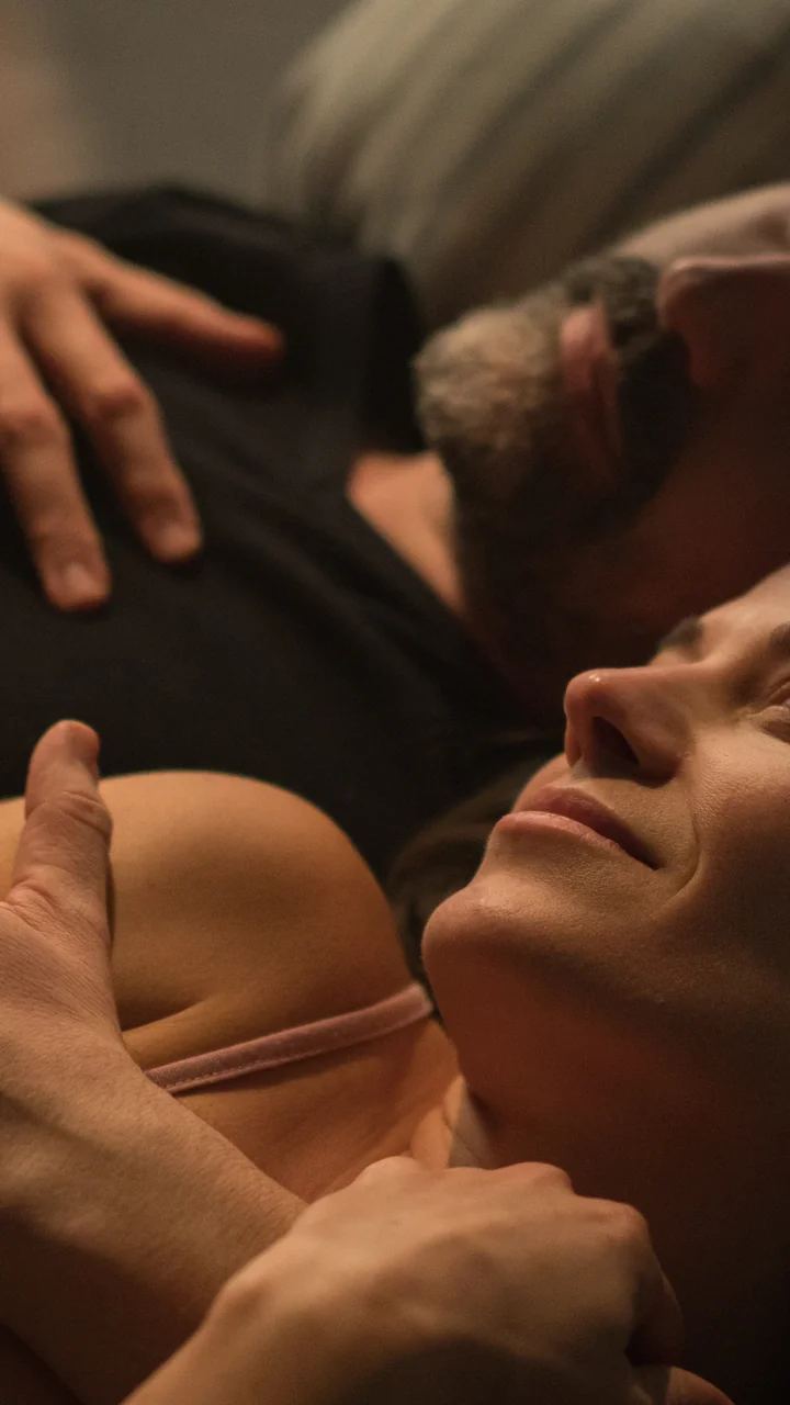 Couple lying together in bed under warm lighting