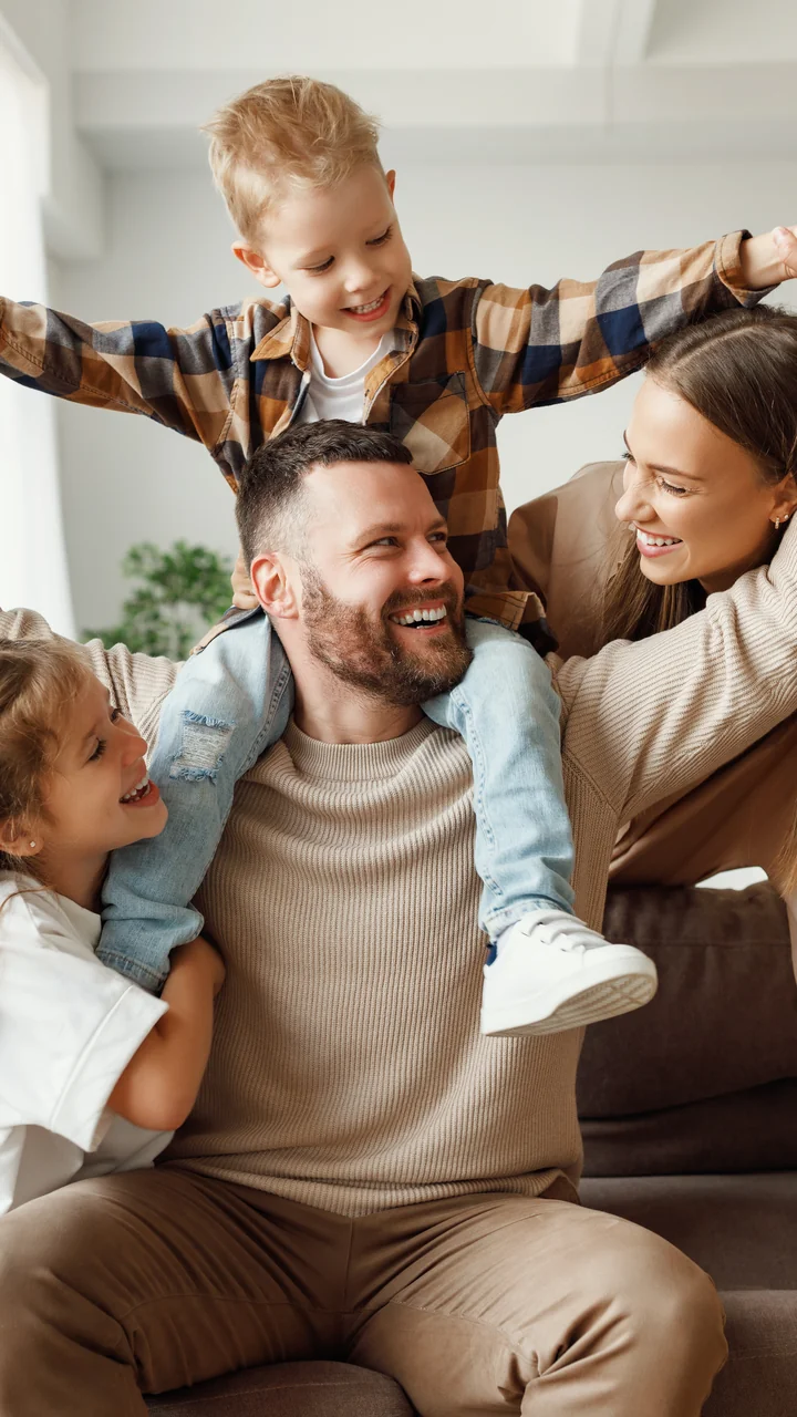 Father and his young family playing together on a couch at home