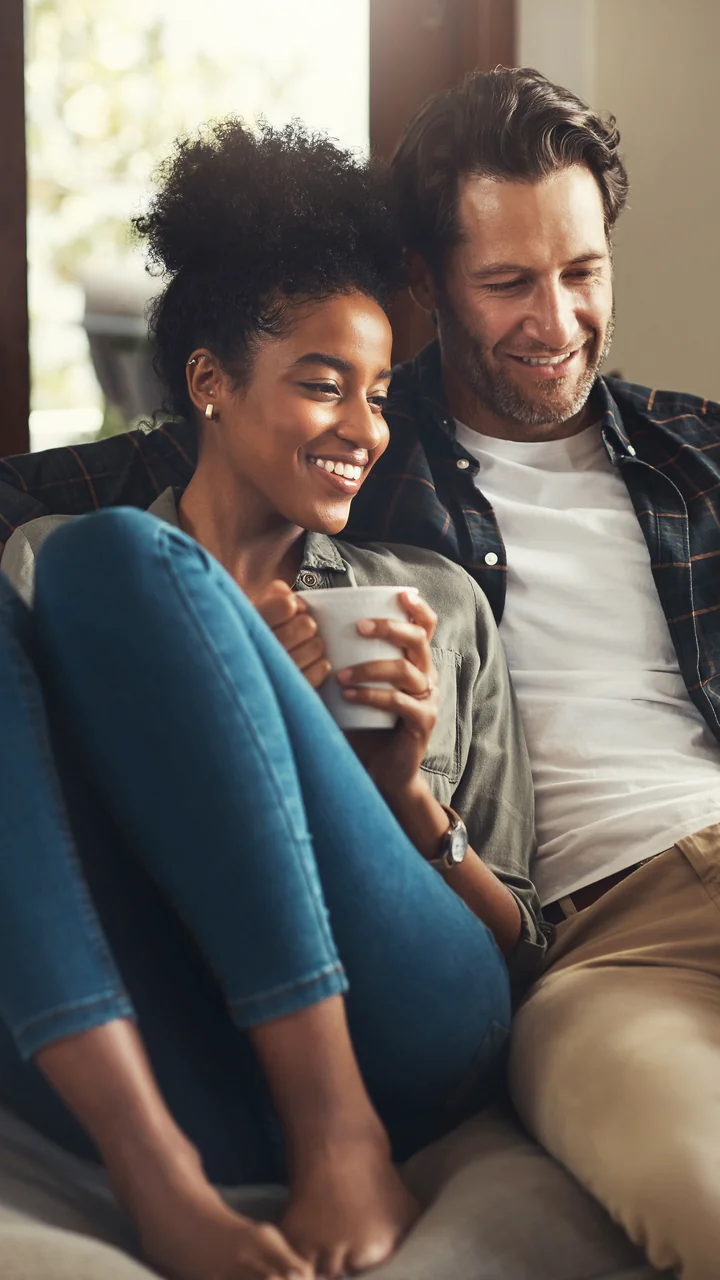Interracial couple sitting on a couch together looking at a phone