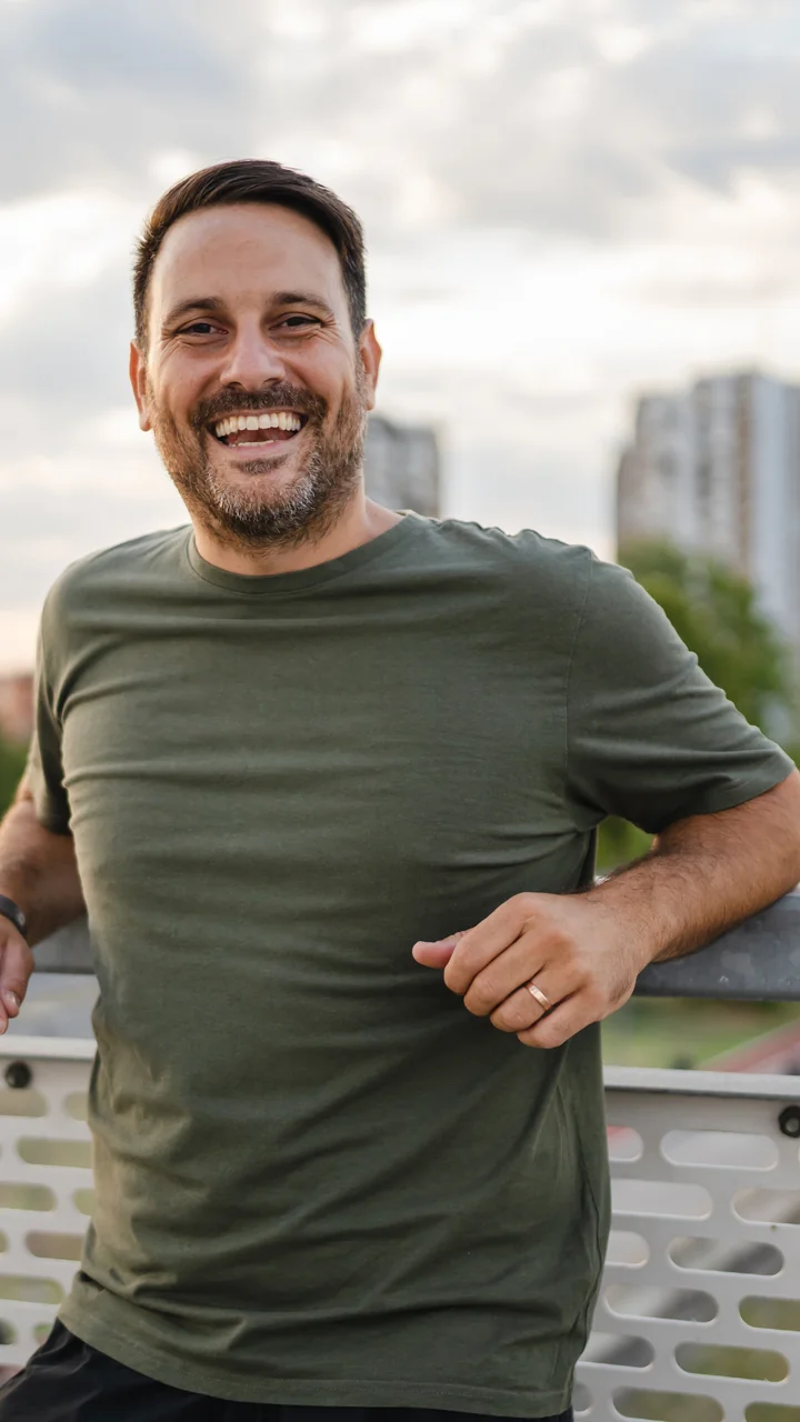 Bearded middle-aged man laughing on a city bridge at dusk