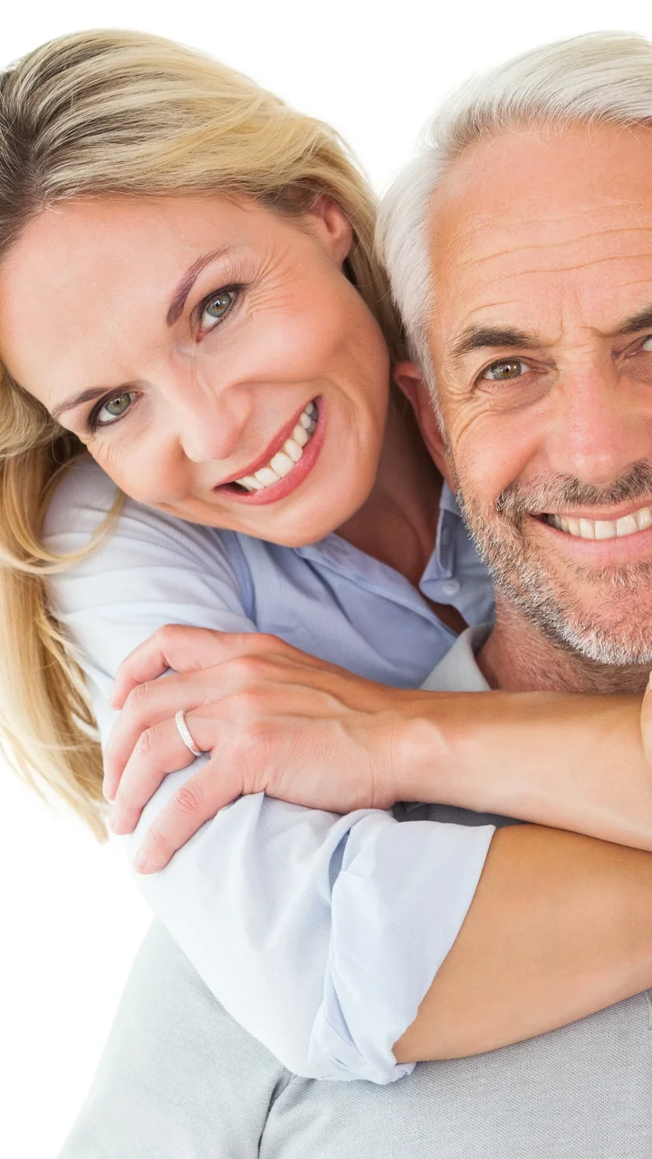 Mature couple in an affectionate embrace smiling against a clean white background