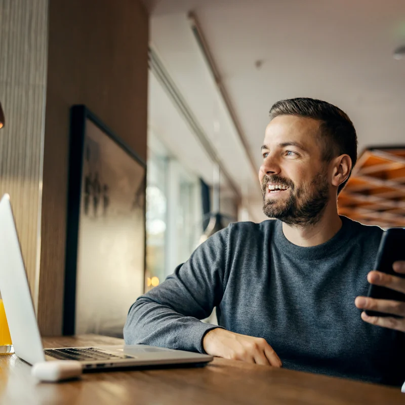 Bearded man reading on his laptop at a morning cafe